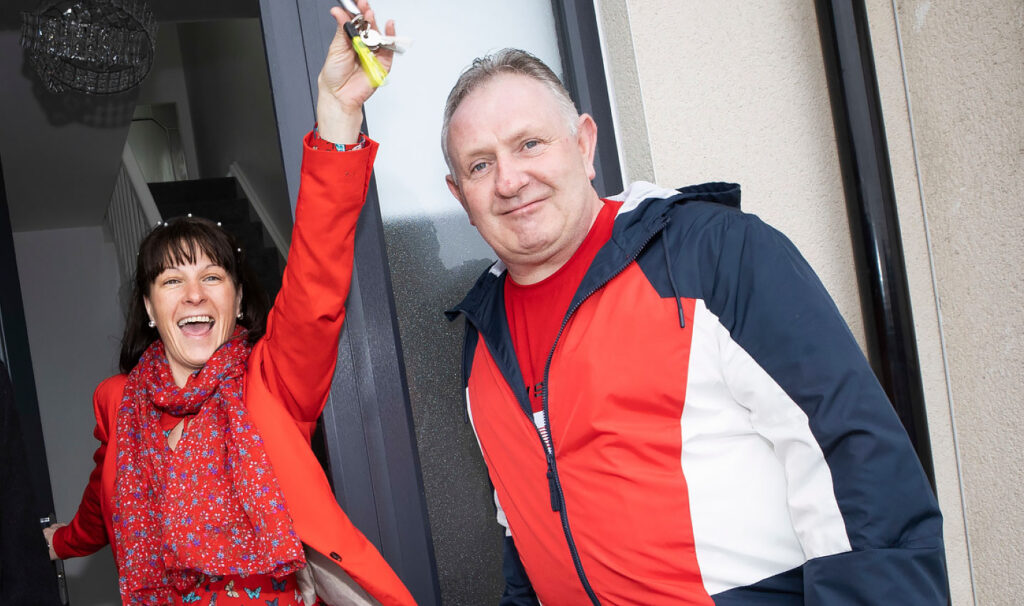 Woman celebrating the keys to her new home alongside her husband.