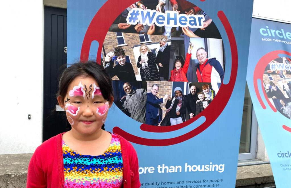 A child standing at a Circle VHA banner with face painting on her face.