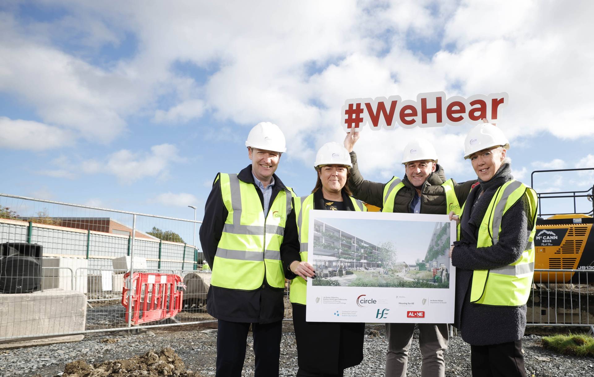 Circle's housing services team holding development drawings and #wehear poster on a building site.